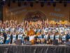 Teamfoto auf der Bühne. Alle lachen und strecken die Arme in die Luft.